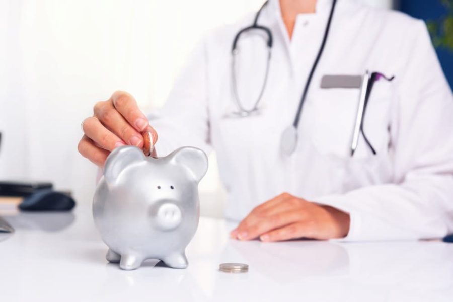 Doctor putting money into a silver piggy bank